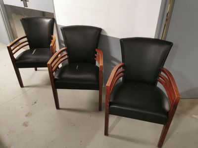 trois fauteuils en cuir noir avec des accoudoirs en bois dans une pièce