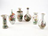 Plusieurs vases aux motifs variés sont disposés en rangée sur une surface blanche