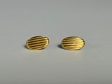 une paire de boucles d'oreilles en or sur une surface blanche