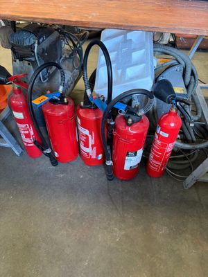 Plusieurs extincteurs sont alignés sur une table dans un garage.