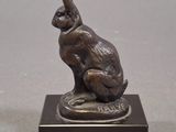 statue of a rabbit sitting on a base on a gray surface