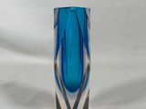 un vase en verre bleu posé sur une surface blanche