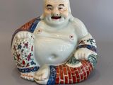 une figurine représentant un Bouddha riant, assis sur un coussin