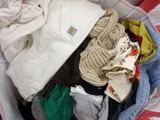 a basket full of clothes sitting on a bed