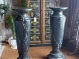two black vases sitting next to each other on the floor