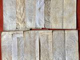 Plusieurs pages de vieux manuscrits sont disposées sur un fond rouge