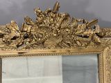 a mirror with a gold frame with a picture of soldiers on it