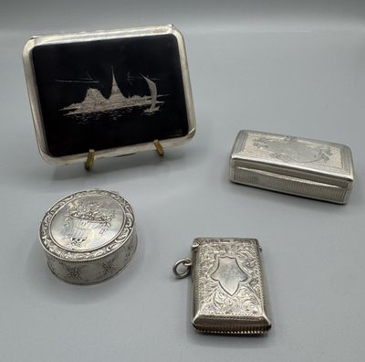 trois objets en argent, dont un briquet, une boîte et une image représentant un bateau