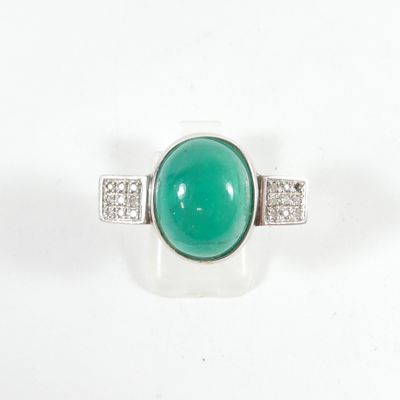 gros plan d'une bague avec une pierre verte et des diamants