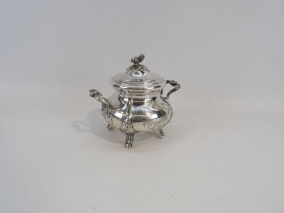 une théière ancienne en argent avec son couvercle, posée sur une surface blanche