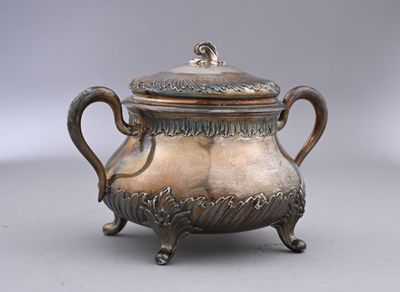 une théière ancienne en métal argenté, avec couvercle, posée sur un socle