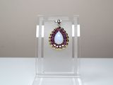 pendentif violet et doré en forme de larme, présenté dans un coffret en acrylique transparent