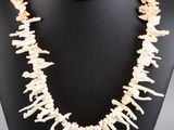 a necklace made of bone and shell beads on a black mannequin