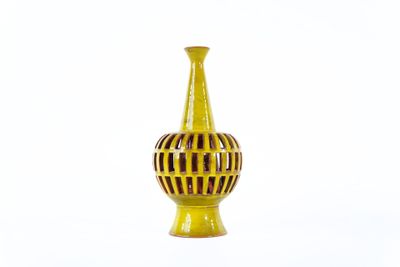 a yellow vase that is sitting on a white surface