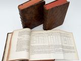 two old books sitting on top of each other on a table