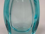 un vase en verre bleu posé sur une surface blanche