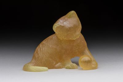 yellow jade figurine of a cat on a white surface