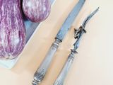 purple eggplant and knife on a plate next to a knife and fork
