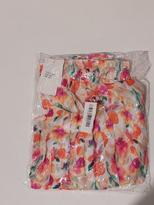 un sac rempli de fleurs orange et roses posé sur une table blanche