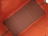 the inside of an orange purse with a brown handle