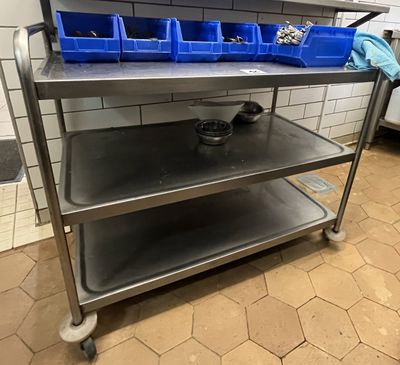 un chariot métallique sur lequel sont posés des bacs bleus, dans une cuisine