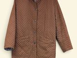 La veste est marron et possède un col à carreaux.