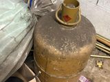 un sac rempli d'objets posé par terre à côté d'une bonbonne de propane