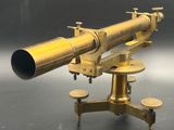 un télescope ancien en laiton posé sur un socle, sur une surface noire