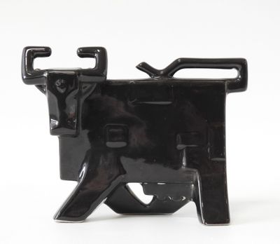 une figurine représentant une vache noire posée sur une surface blanche