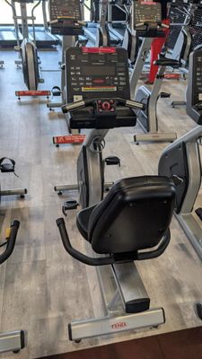rows of stationary exercise bikes in a gym with a wooden floor