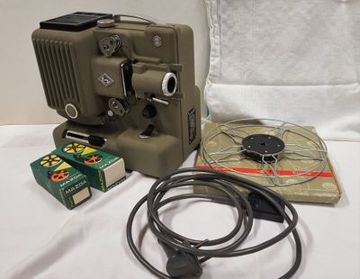 un vieux projecteur de cinéma posé sur une table à côté d'un paquet de cigarettes