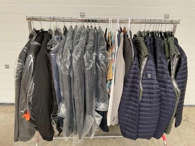 de nombreuses vestes suspendues à un portant dans un garage