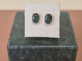 un gros plan sur une paire de boucles d'oreilles en émeraude posées sur un bloc de marbre