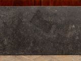 a black marble block on the floor next to a wooden cabinet