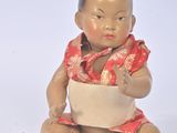 une petite poupée représentant un bébé assis par terre