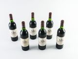 six bottles of wine are lined up on a white surface
