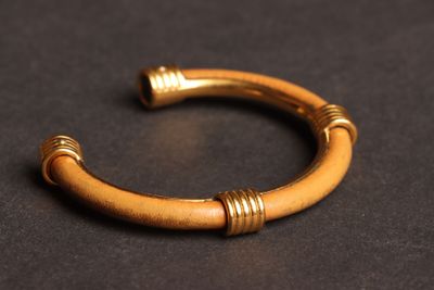 gros plan d'un bracelet en or sur une surface noire