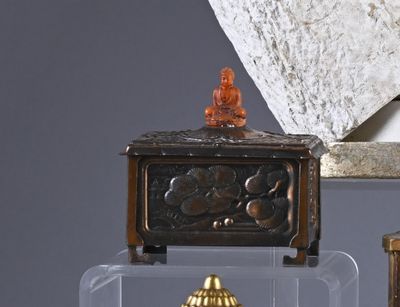 a small clock sitting on top of a table next to a vase