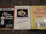 trois livres posés sur une table, avec un chef debout à côté