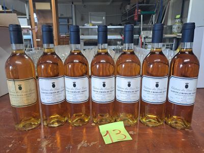 Six bouteilles de vin sont alignées sur une table, accompagnées d'une étiquette de prix