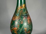 un vase vert posé sur un socle, sur une surface grise