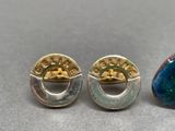 two pairs of earrings are sitting on a table next to each other