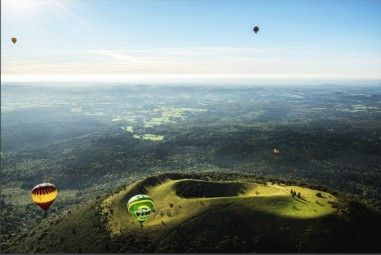 de nombreuses montgolfières survolant une colline verdoyante