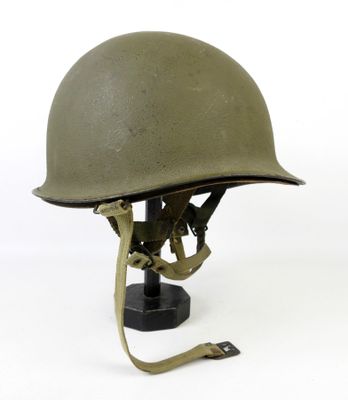 un casque militaire posé sur un socle, sur fond blanc