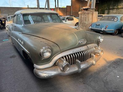 an old car parked in a parking lot with other cars