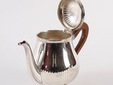 an antique silver teapot with a wooden handle on a white background