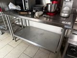 a stainless steel table in a kitchen with a red mixer on it