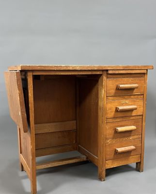un vieux bureau en bois muni de tiroirs, avec un tiroir en dessous