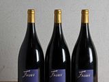 three bottles of wine are lined up on a wooden table