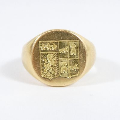 a close up of a gold signet ring with a coat of arms on it